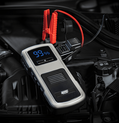 Car jump starter with digital display sitting on a car engine