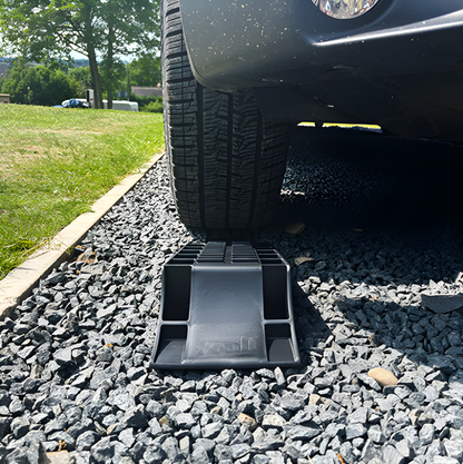Car tire parked on a black Maypole MP4603 Froli level ramp on a gravel surface outdoors