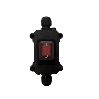 A black plastic electrical switch box with a red rocker switch and black cable glands on the top and bottom, isolated on a white background.